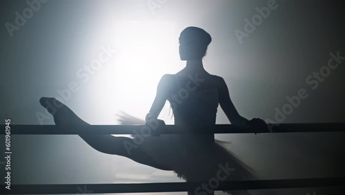 Ballerina practices dance moves near the ballet barre in the hall. Silhouette of a beautiful dancing girl. The art of choreographic movements. High quality 4k footage
