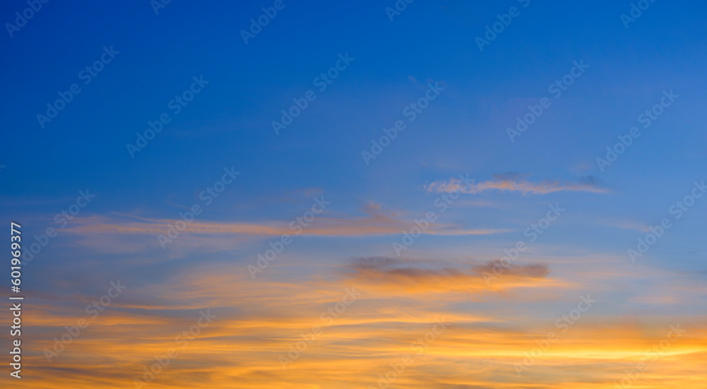 Dramatic Dusk Sky Background in the Evening with majestic yellow sunlight and clouds on blue Twilight after sundown