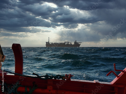 Distant Ship on Choppy Seas Under Stormy Sky

Description: A large vessel navigates rough waters under a dramatic, cloudy sky with visible rain shafts, viewed from the deck of another ship