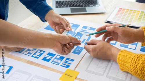 Close-up ux developers and ui designers use augmented reality to brainstorm on mobile app interface wireframe designs on modern office desks. Creative digital development office