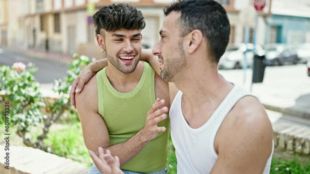 Two men couple hugging each other sitting on bench at park Two men couple hugging each other sitting on bench at park