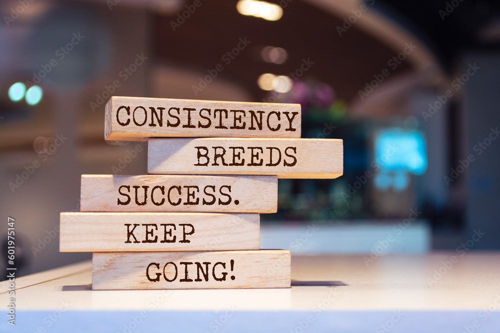 Wooden blocks with words 'Consistency breeds success. Keep going'.