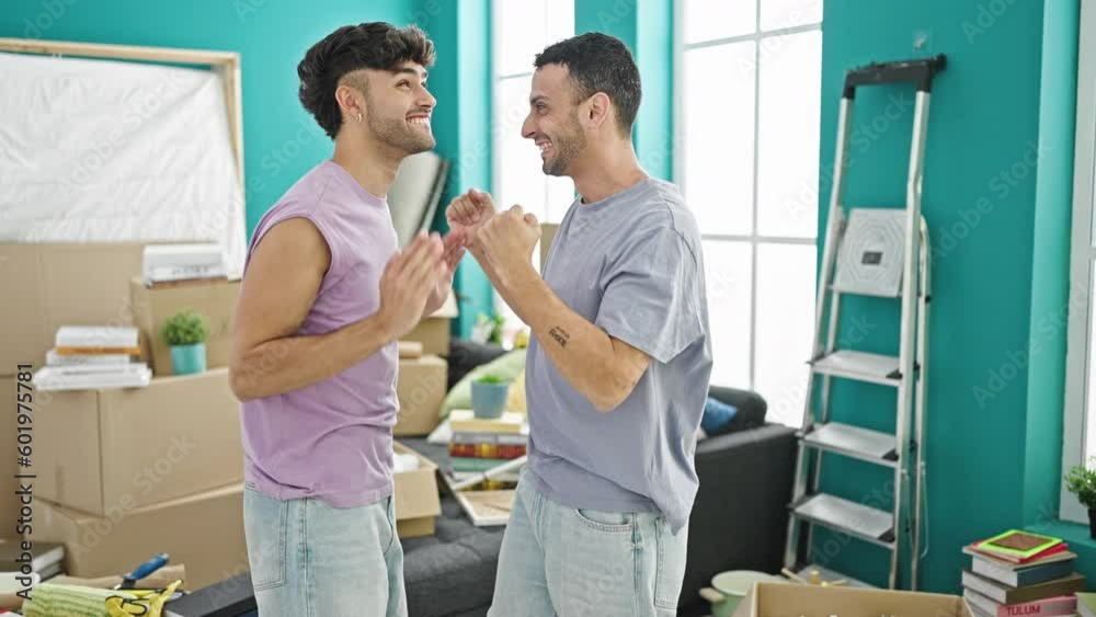 Two men couple hugging each other standing at new home Two men couple hugging each other standing at new home