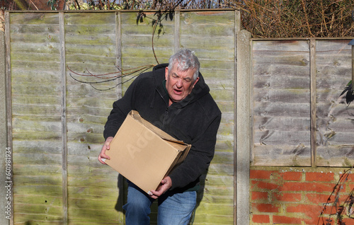 Φωτογραφία Struggling lifting a box that is too heavy and causing injury.