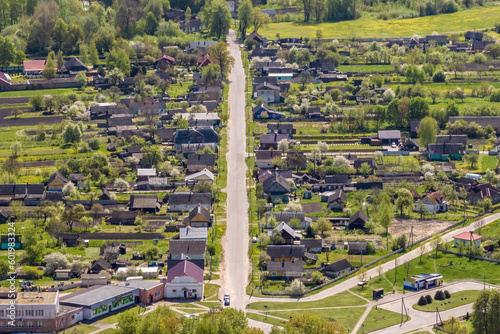 panoramic aerial view of eco village with wooden houses, gravel road, gardens and orchards