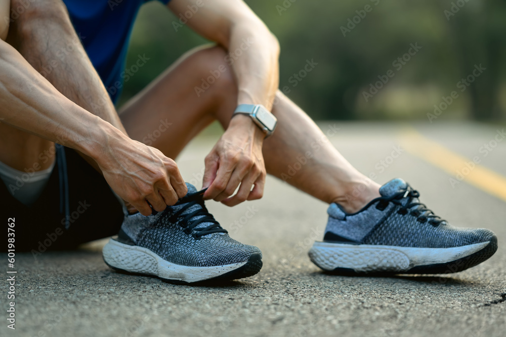 Close up of male athlete tying shoelace get ready to running workout. Healthy lifestyle and wellness concept