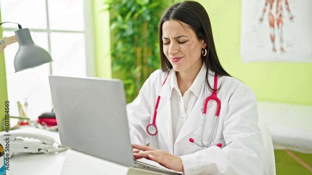 Young beautiful hispanic woman doctor stressed for cervical pain working at clinic Young beautiful hispanic woman doctor stressed for cervical pain working at clinic