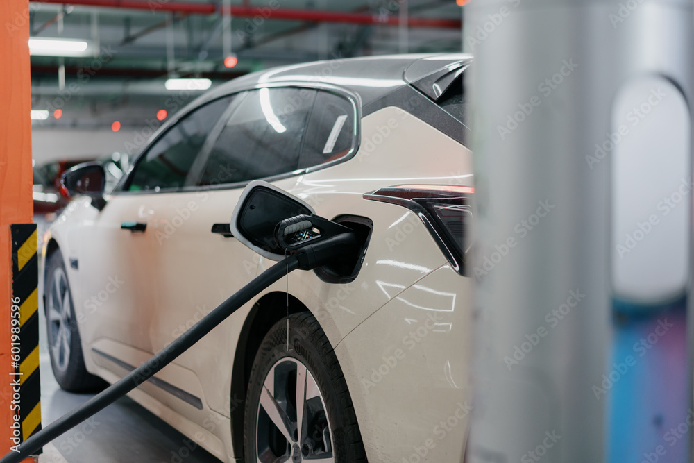 Naklejka premium Electric car is charging in station