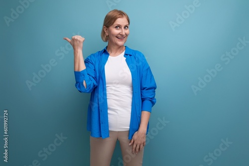 confident blonde 50s woman on blue background with copyspace