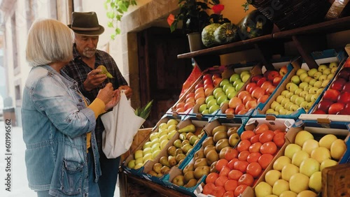 Happy senior couple buying fruits and vegetables at the market - Shopping food concept