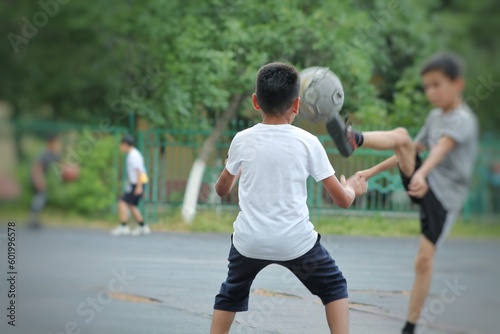 children playing football with an old sword in the yard. The goalkeeper catches the ball.