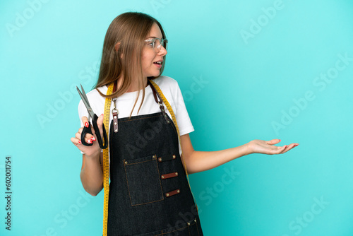 Young Lithuanian seamstress woman isolated on blue background with surprise expression while looking side