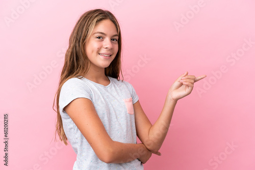 Little caucasian girl isolated on pink background pointing finger to the side