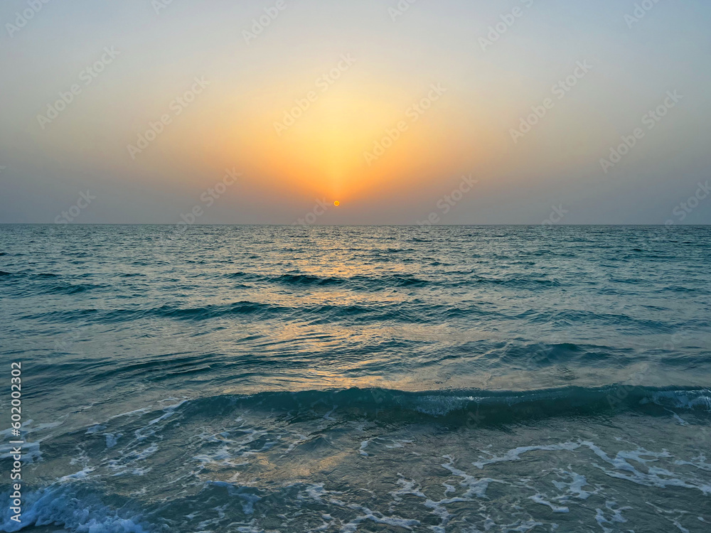 The Beauty of Sunset waves. Evening seascape with empty coastline of sand beach in United Arab Emirates. The waters edge sealine Abu Dhabi beach with sunset. The Beauty of Sunset waves. Evening seascape with empty coastline of sand beach in United Arab Emirates. The waters edge sealine Abu Dhabi beach with sunset.
