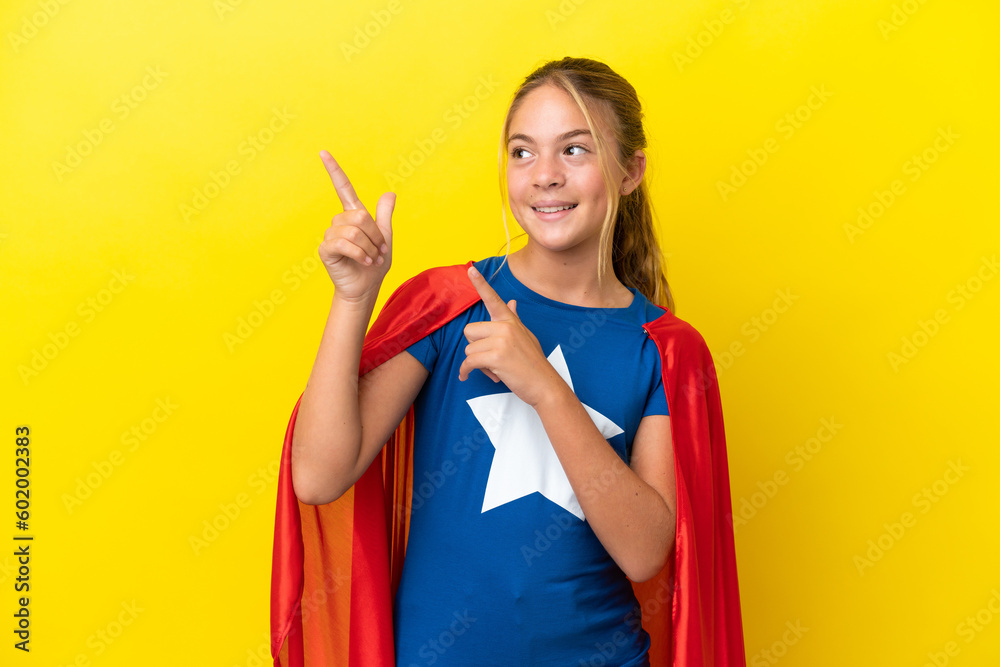 Super Hero little girl isolated on yellow background pointing with the index finger a great idea Super Hero little girl isolated on yellow background pointing with the index finger a great idea
