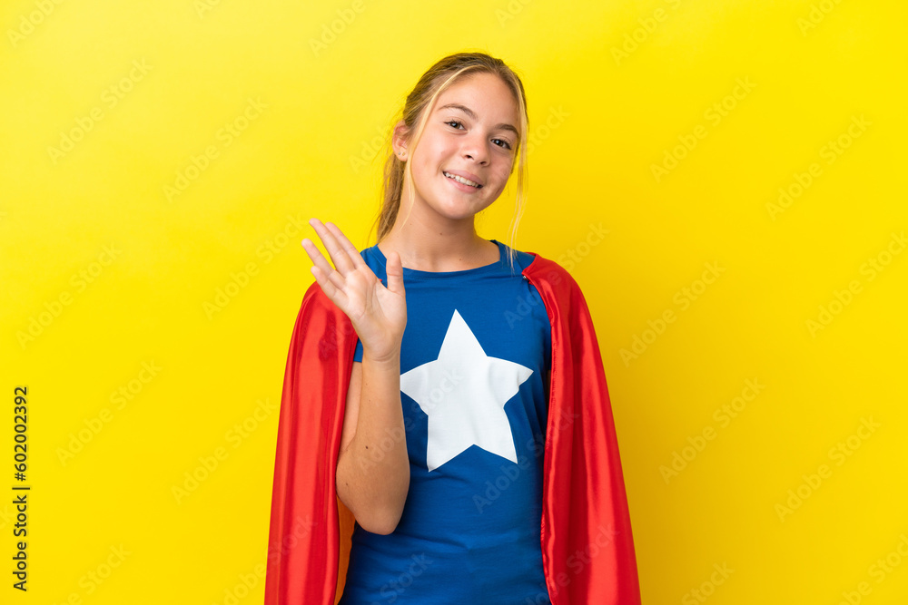 Super Hero little girl isolated on yellow background saluting with hand with happy expression Super Hero little girl isolated on yellow background saluting with hand with happy expression