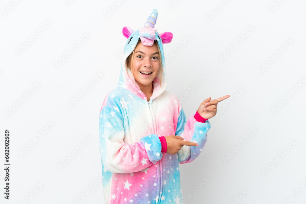 Little girl with unicorn pajamas isolated on white background surprised and pointing side Little girl with unicorn pajamas isolated on white background surprised and pointing side