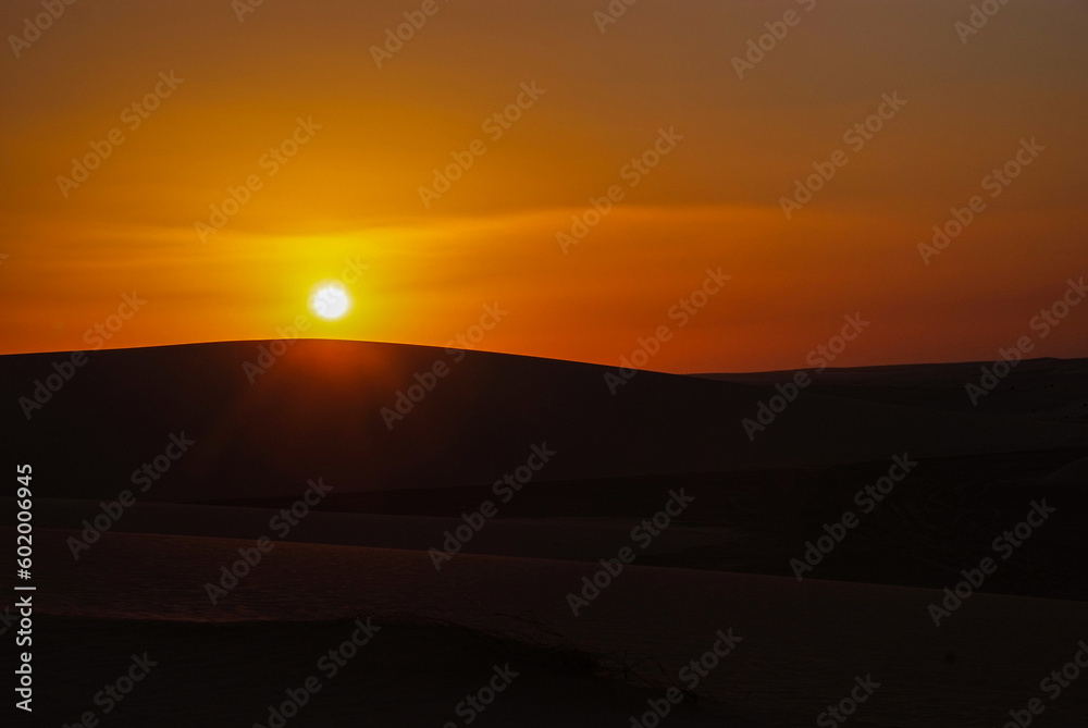 Sunset and sunrise in the desert with beautiful sand dunes behind it
