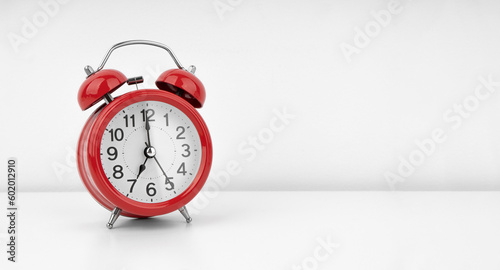 Red alarm clock on white wall background