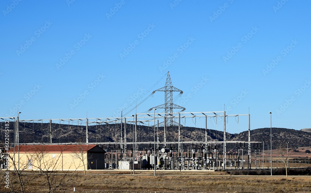 General view of an electrical substation in the middle of the countryside with many tall poles and wiring lines General view of an electrical substation in the middle of the countryside with many tall poles and wiring lines