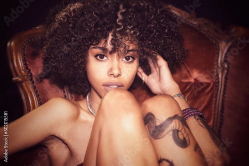 Tattoed alternative young woman with natural afro hair and piercings posing on a victorian armchair in sparkly disco dress (6/6)