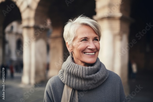 Portrait of smiling mature woman in scarf and coat looking at camera in the city