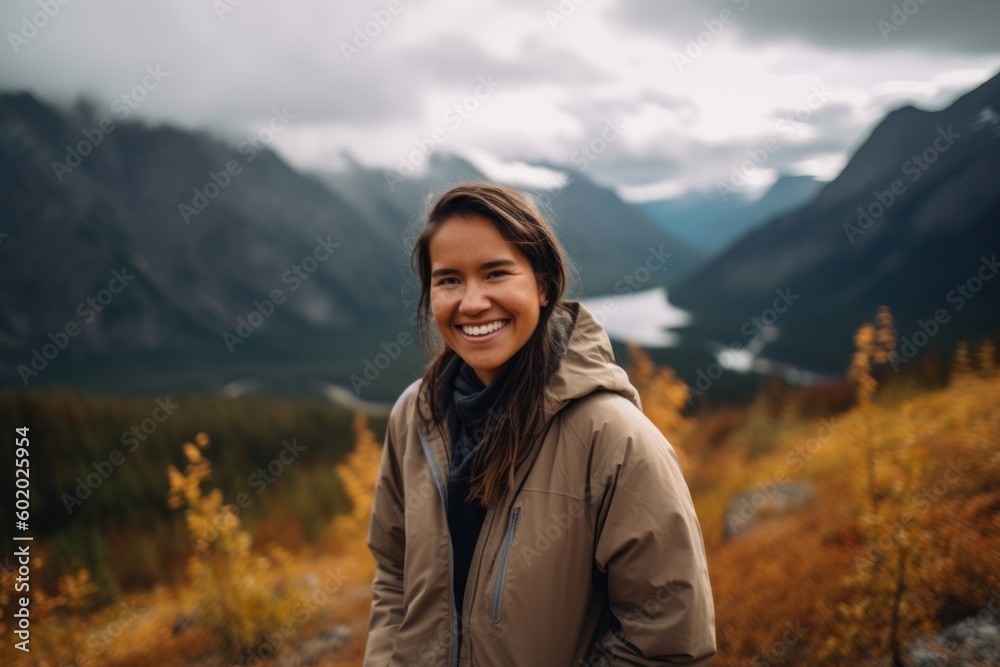 Beautiful young woman hiker smiling and looking at camera in autumn mountains