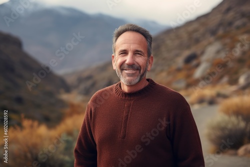Handsome middle-aged man in a brown sweater in the mountains