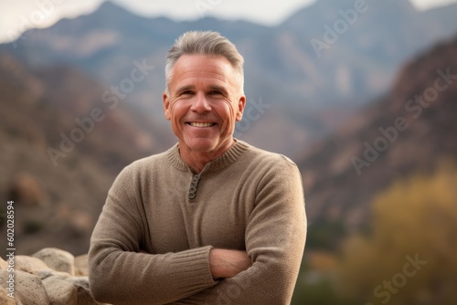 Portrait of a happy senior man smiling with arms crossed in the mountains