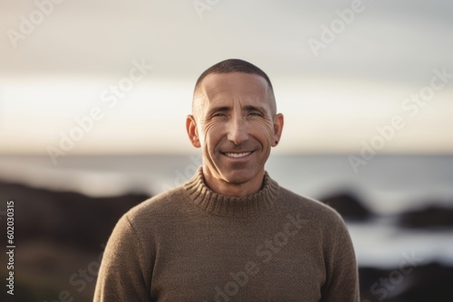 Portrait of smiling mature man standing against blurred background at beach during sunset
