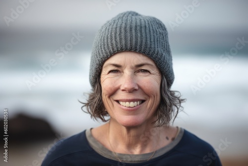 Portrait of smiling senior woman on beach with hat looking at camera