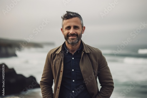 Portrait of a handsome man standing on the beach by the ocean