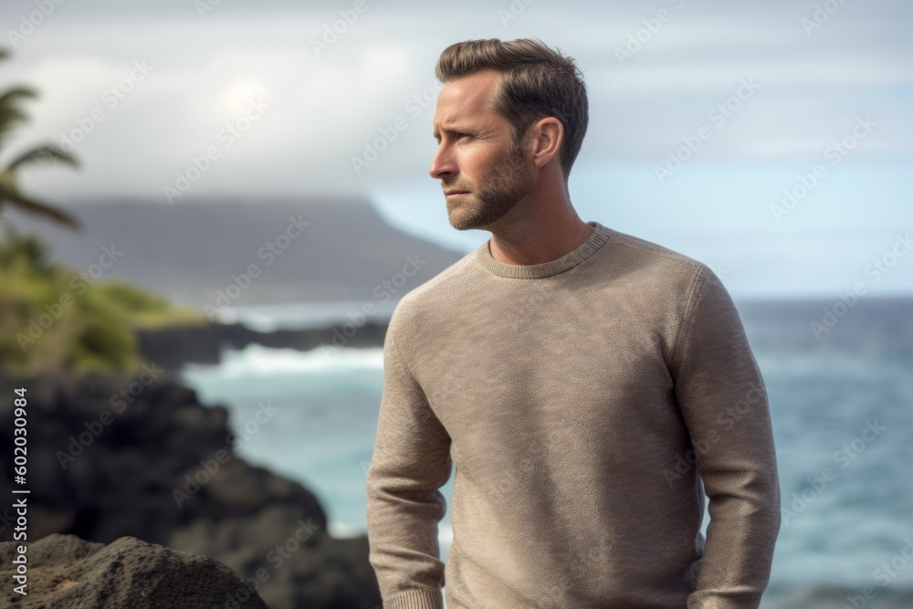 Handsome man standing in front of the ocean looking to the horizon Handsome man standing in front of the ocean looking to the horizon