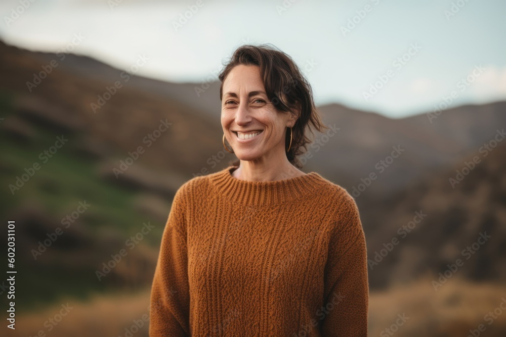 Portrait of a smiling middle-aged woman in sweater standing outdoors
