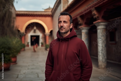 Portrait of a man in a red hooded sweatshirt on the background of an ancient building