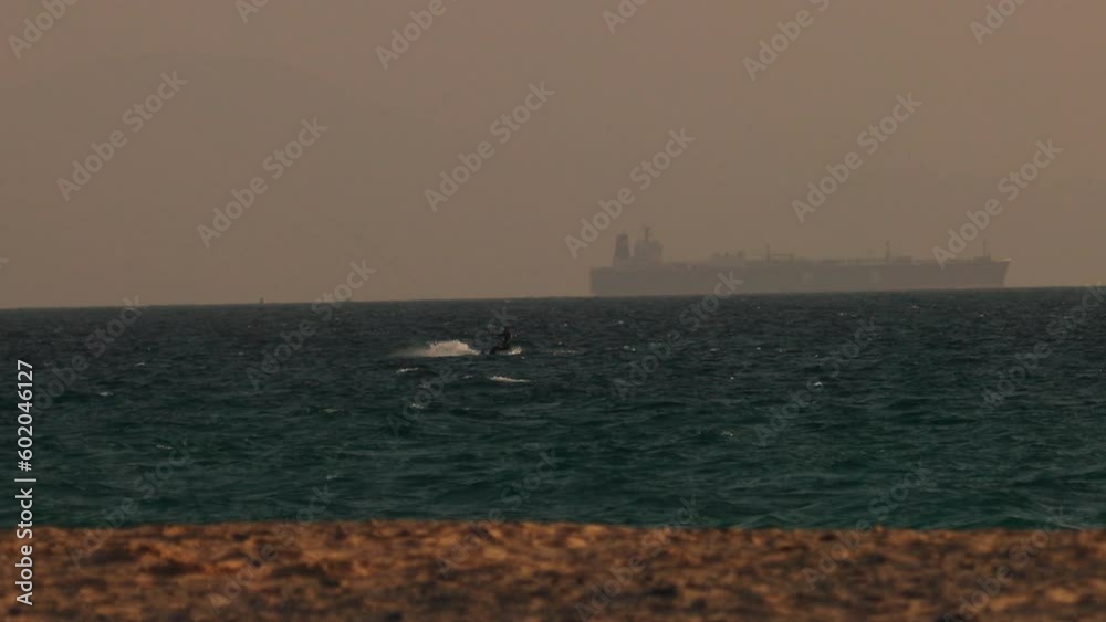 Windsurfer On Water Against Background Of Sea. In Sea Large Ship Behind Fog In Distance. Windsurfer On Water Against Background Of Sea. In Sea Large Ship Behind Fog In Distance.