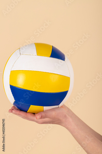 Hands holding volleyball. ball in hands. Isolated on pastel orange, peach background.