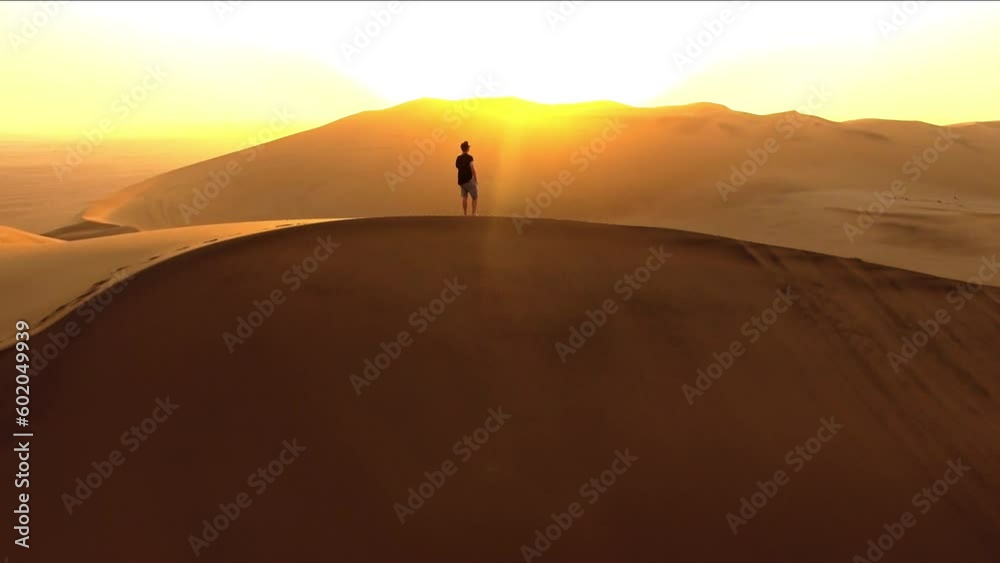 Sunset, drone and man walking in desert for hiking, adventure and freedom. Travel, discover and expedition hobby with person silhouette thinking on sand dunes hill for explorer, vacation and journey Sunset, drone and man walking in desert for hiking, adventure and freedom. Travel, discover and expedition hobby with person silhouette thinking on sand dunes hill for explorer, vacation and journey