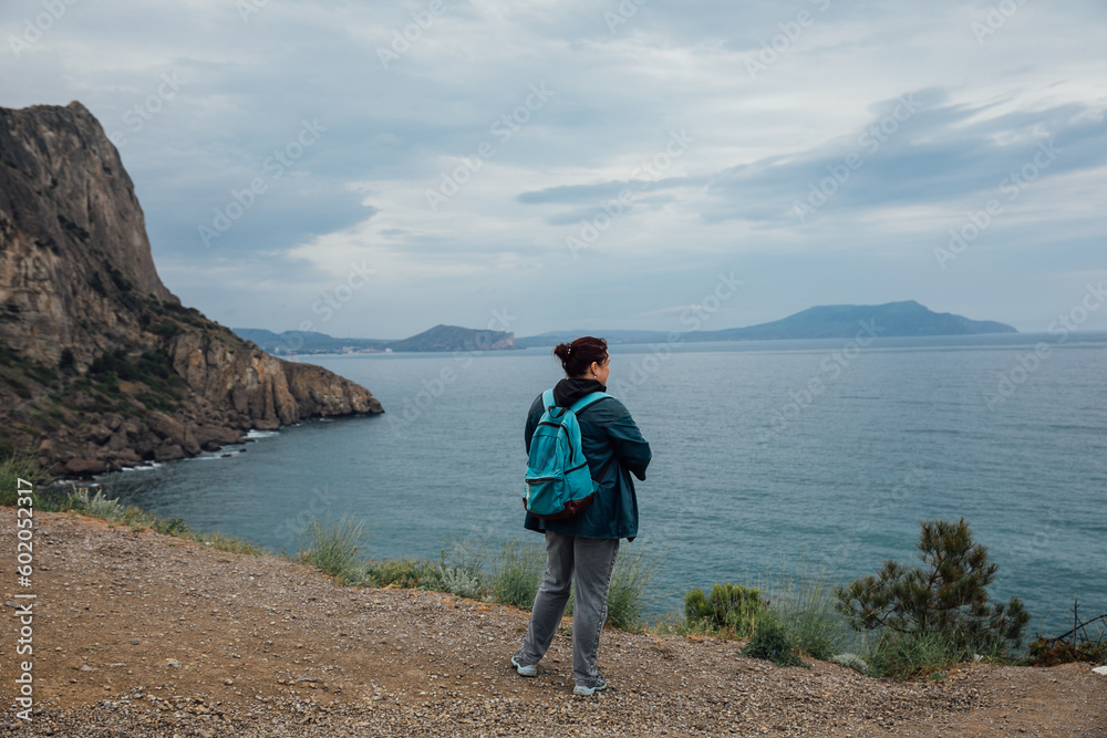 woman with backpack looks at the sea on the mountain travel hiking nature
