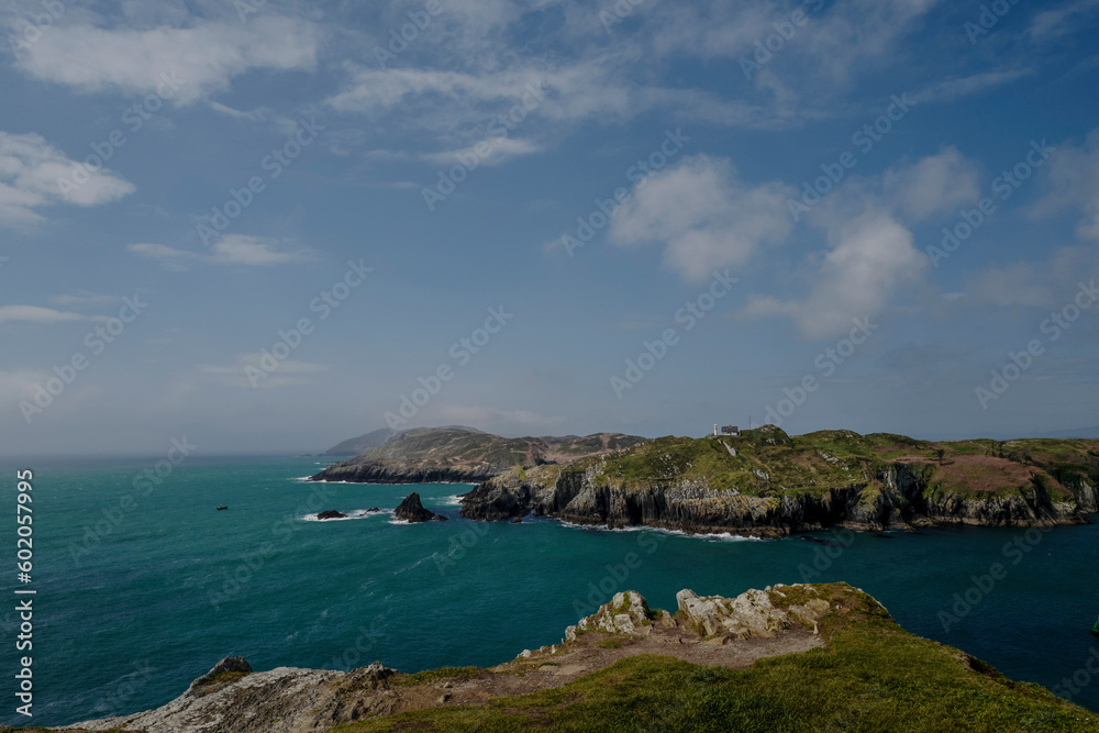shoreline with impressive cliffs and an old lighthouse in  bright summer weather scenery