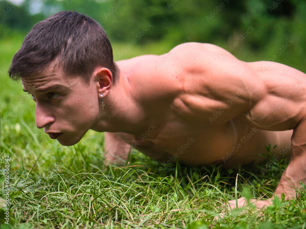 Close-up of topless young sportsman doing exercise in a park Close-up of topless young sportsman doing exercise in a park