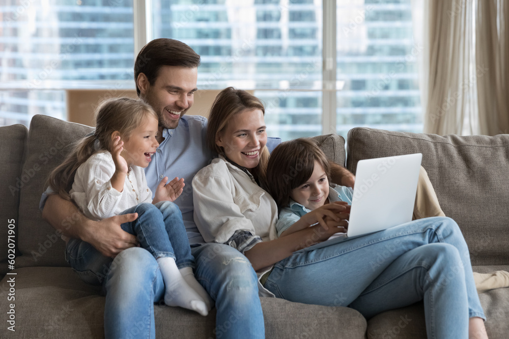 Happy couple of parents using online learning app on laptop, for educating little kids, resting on couch together, holding digital device, enjoying wireless technology, domestic internet connection Happy couple of parents using online learning app on laptop, for educating little kids, resting on couch together, holding digital device, enjoying wireless technology, domestic internet connection