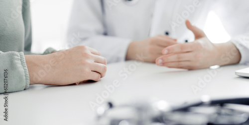 Doctor and patient discussing current health examination while sitting at the desk in clinic office, closeup. Medicine concept