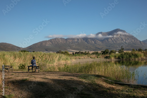 Bird watcher next to a dam with a mountain in the background