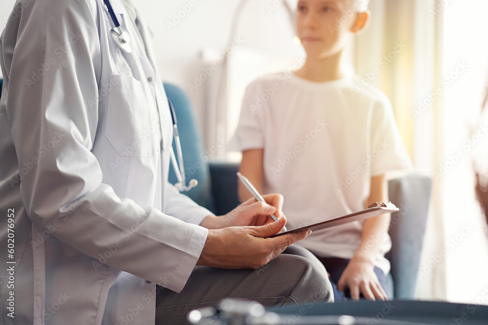 Doctor woman and kid patient at home. The pediatrician fills up medical form, close up. Medicine, healthcare concepts Doctor woman and kid patient at home. The pediatrician fills up medical form, close up. Medicine, healthcare concepts
