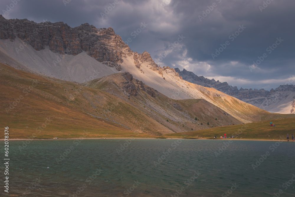 People resting around the mountain lake Lac de Soulier in the Queyras valley in the Alps (Hautes-Alpes, France) People resting around the mountain lake Lac de Soulier in the Queyras valley in the Alps (Hautes-Alpes, France)