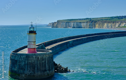 The entrance to Newhaven harbour, East Sussex, UK and its breakwater and lighthouse. Clear blue skiy and water with white cliffs in the background. photo