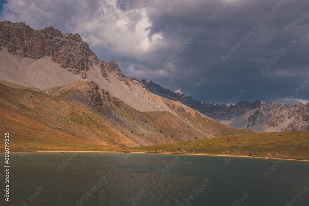 People resting around the mountain lake Lac de Soulier in the Queyras valley in the Alps (Hautes-Alpes, France)