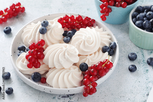 White sweet traditional merenques with berries on the plate