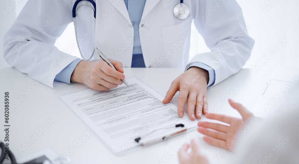 Doctor and patient discussing current health questions while sitting near of each other and using clipboard at the table in clinic, just hands closeup. Medicine concept Doctor and patient discussing current health questions while sitting near of each other and using clipboard at the table in clinic, just hands closeup. Medicine concept